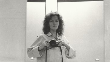 1/2 length self portrait in mirror, wearing pyjama shirt, camera at shoulder height, 1979 Carol Jerrems