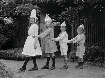 Two girls and two boys wearing party hats, standing in line by Ruth Hollick