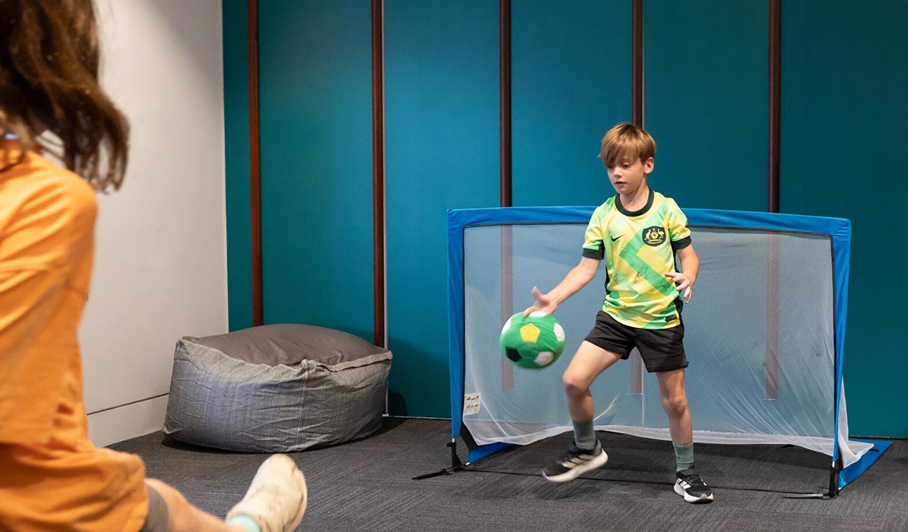 Children playing indoor soccer in front of a goal
