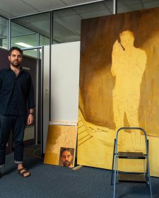 Christopher Bassi standing in an empty office next to a large yellow painting
