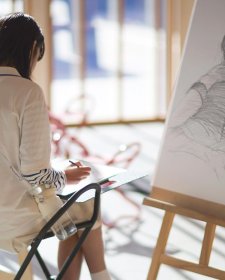 A person drawing on paper in front of an easel A person drawing on paper in front of an easel