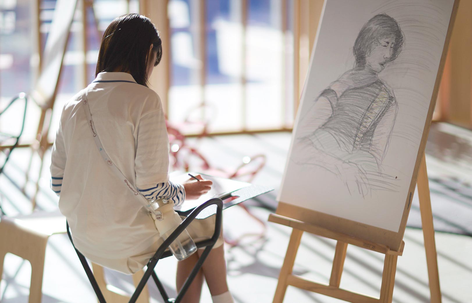 A person drawing on paper in front of an easel