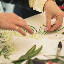 Hands arranging flower fragments on a table Hands arranging flower fragments on a table