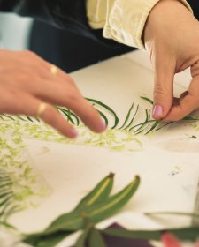 Hands arranging flower fragments on a table Hands arranging flower fragments on a table