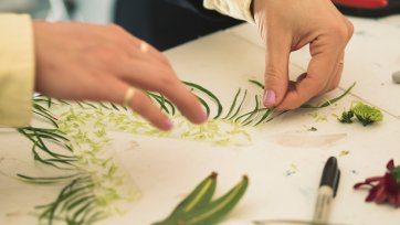 Hands arranging flower fragments on a table