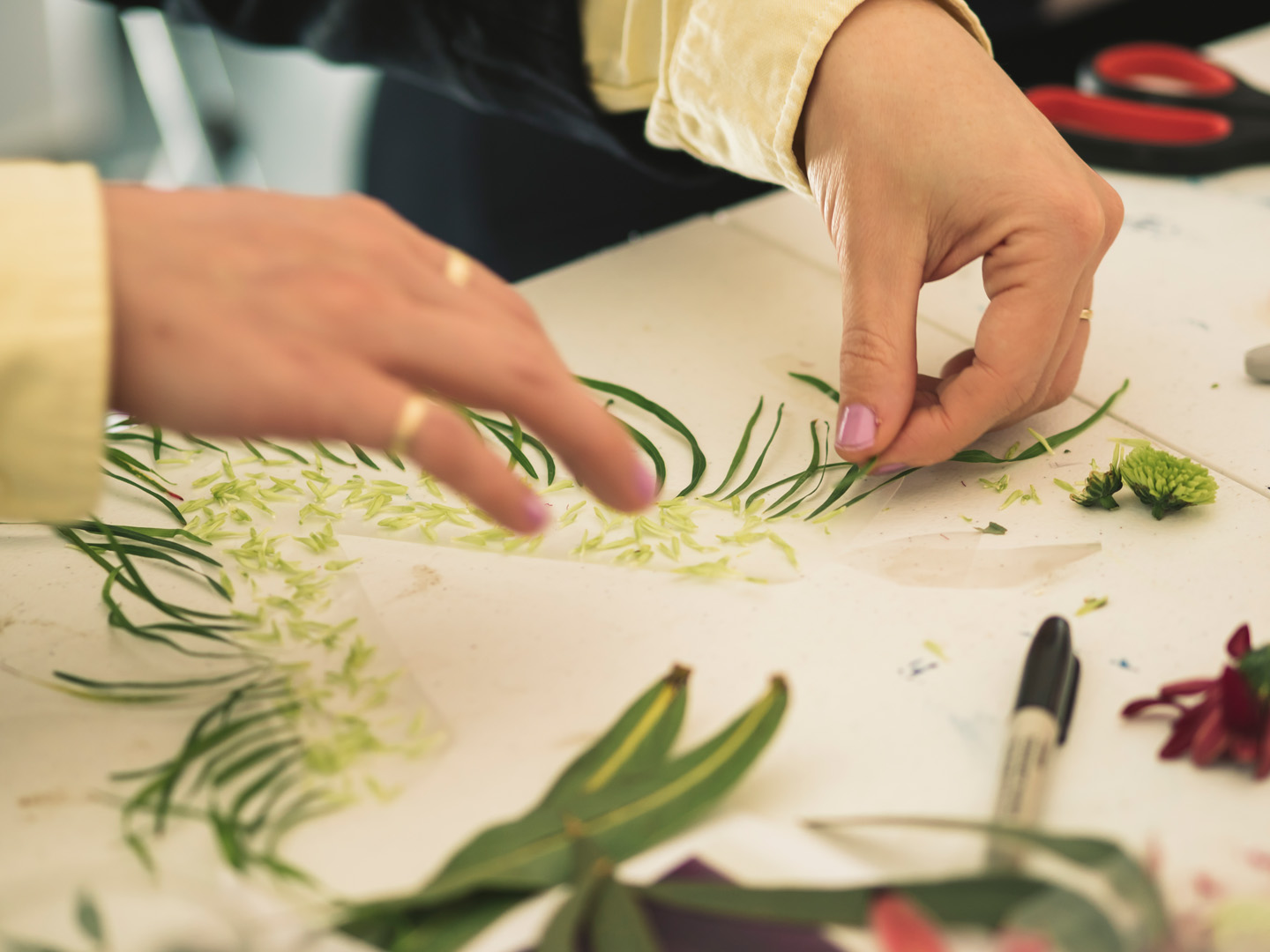 Hands arranging flower fragments on a table