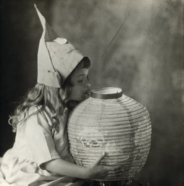 Young girl holding a Chinese paper lantern, wearing a hat