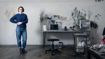 Fiona McMonagle standing in her studio with paint splatters on the white walls