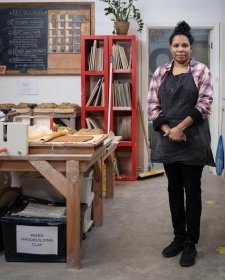 Naomi Hobson standing next to a wooden table and metal sink in her studio