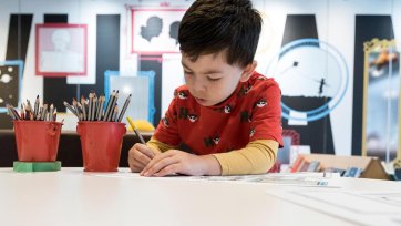 A boy drawing on paper with a pencil