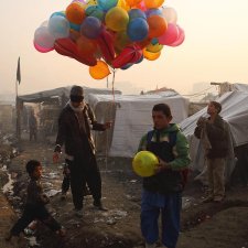At sunrise, a balloon seller makes his way through an informal settlement for families displaced by fighting in Afghanistan’s provinces, beside Kabul’s national cricket stadium, 2014 Andrew Quilty