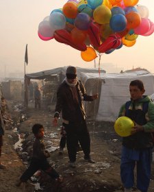 At sunrise, a balloon seller makes his way through an informal settlement for families displaced by fighting in Afghanistan’s provinces, beside Kabul’s national cricket stadium, 2014 Andrew Quilty