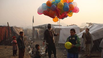 At sunrise, a balloon seller makes his way through an informal settlement for families displaced by fighting in Afghanistan’s provinces, beside Kabul’s national cricket stadium, 2014 Andrew Quilty