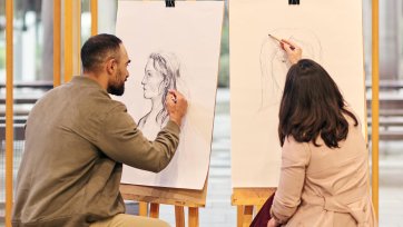 Two people drawing at easels