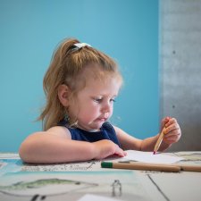A child drawing on paper at a table A child drawing on paper at a table