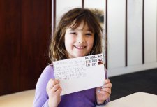 A girl with a postcard in the Brack x McKenna Creative Space