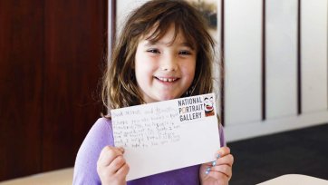 A girl with a postcard in the Brack x McKenna Creative Space