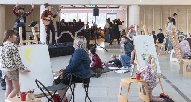 Musicians performing while people draw on easels