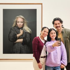 People using a phone to take a photo in front of an artwork