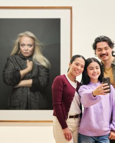 People using a phone to take a photo in front of an artwork