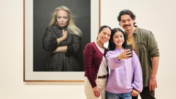 People using a phone to take a photo in front of an artwork