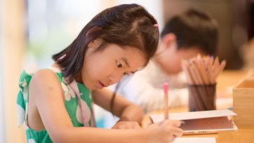 A child drawing at a wooden table A child drawing at a wooden table