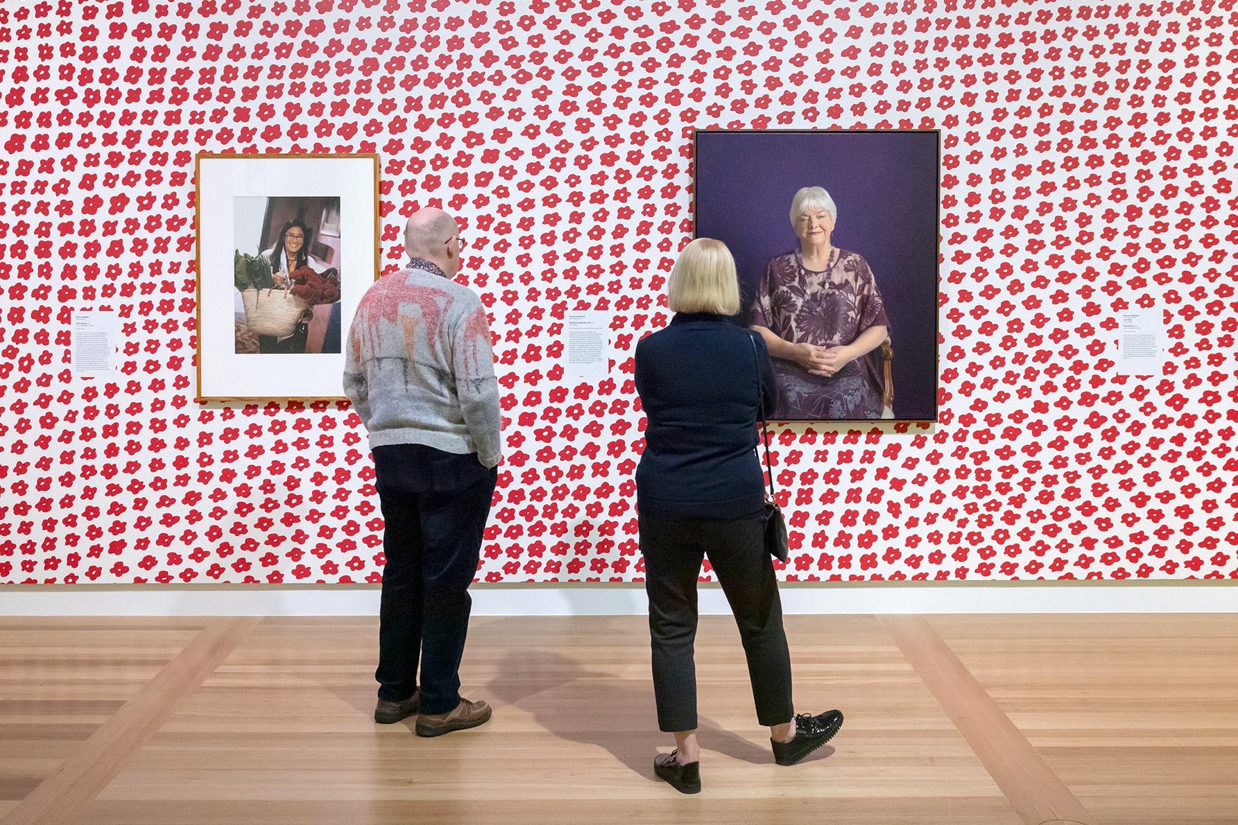 Two people viewing artworks in the In Bloom exhibition