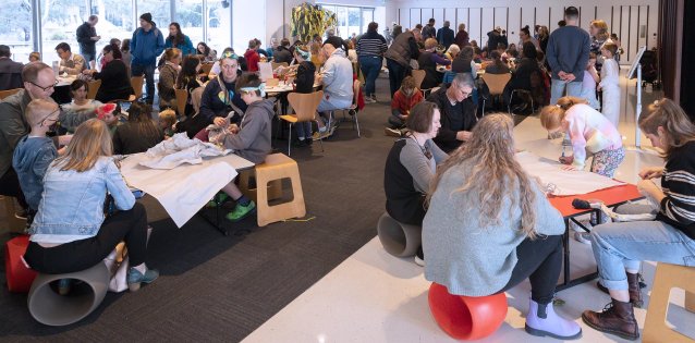 People sitting at tables participating in creative activities