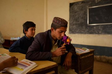 A student with flowers collected on the way to school in Sayedabad, Nad-I Ali district, Helmand, 2016 Andrew Quilty