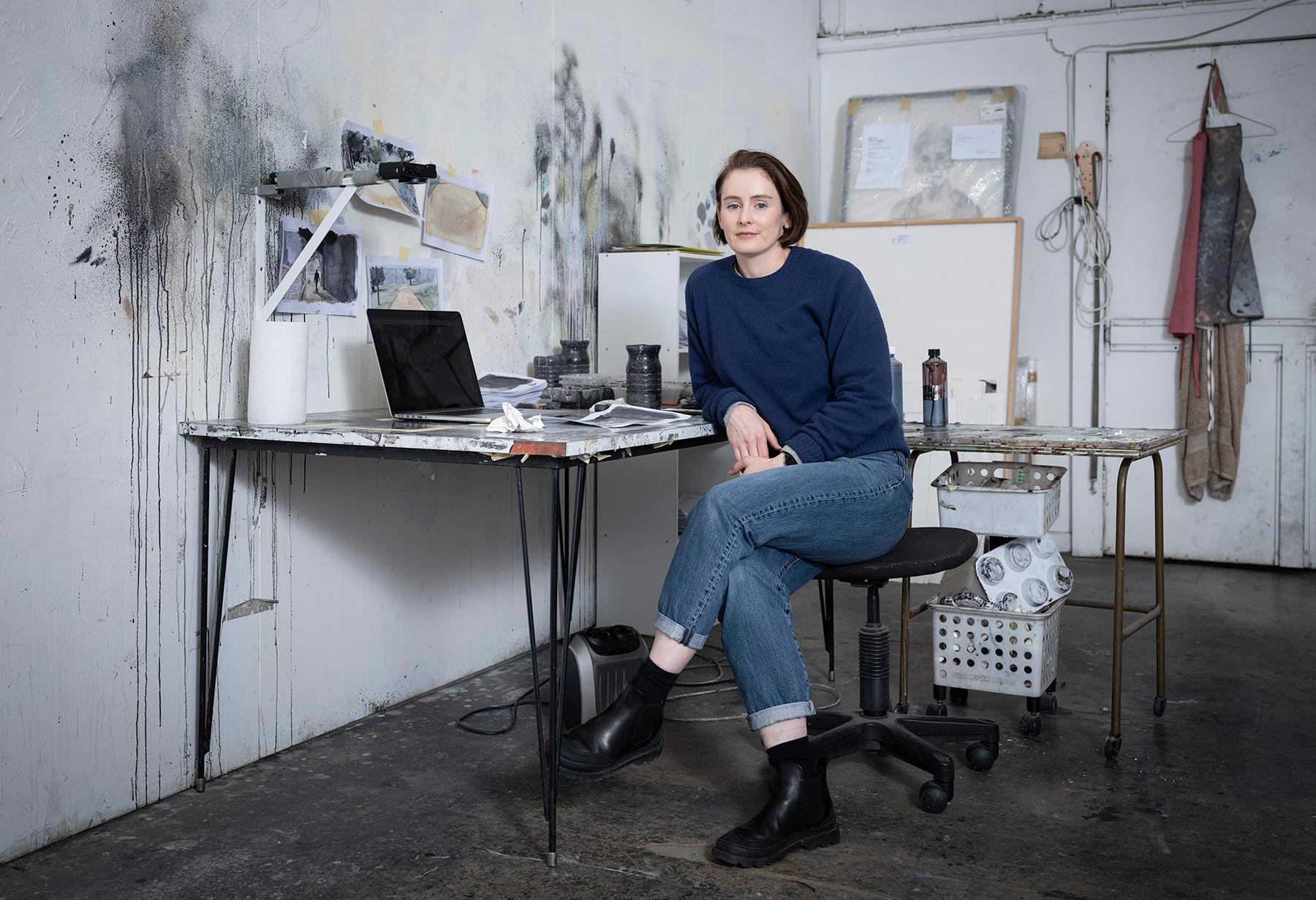 Fiona McMonagle sitting in her studio with paint splatters on the white walls