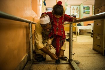 Four-year-old Marwa stands on her prosthetic leg for the first time with the help of her father at the orthopaedic centre in Nangarhar’s capital, Jalalabad, 2018 Andrew Quilty